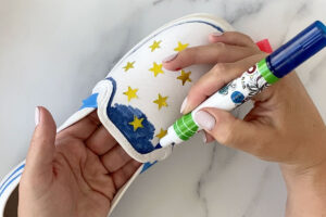 Canvas shoe with star stickers on it; hand coloring it with blue fabric marker