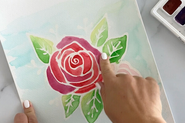 Using fingers to rub the rubber cement outline off the floral painting