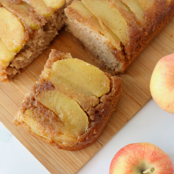 Sliced of apple upside down cake on a cutting board; apples