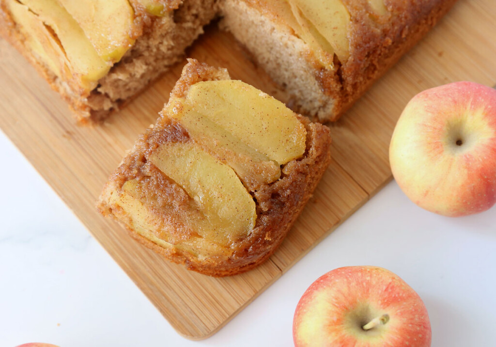 Sliced of apple upside down cake on a cutting board; apples