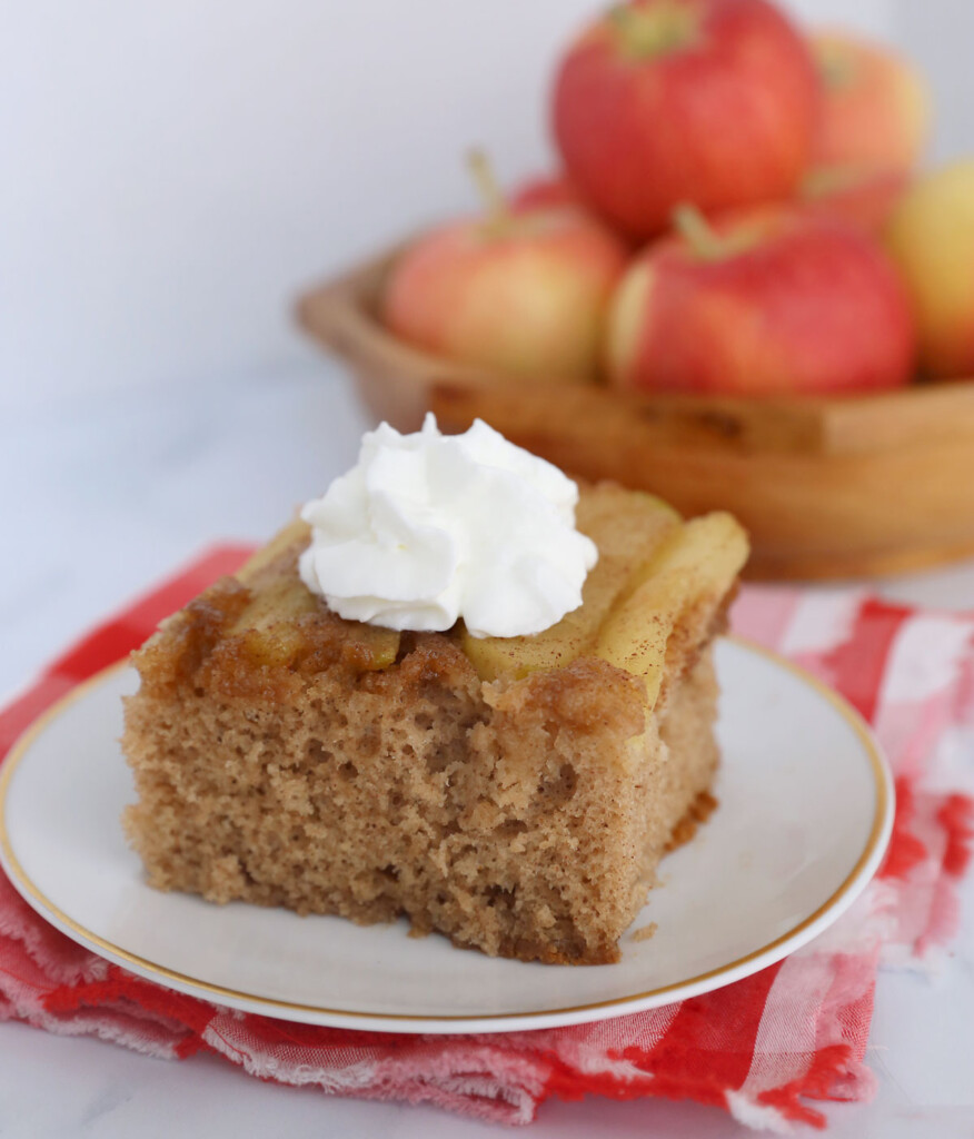 Piece of apple upside down cake on a plate with whipped cream
