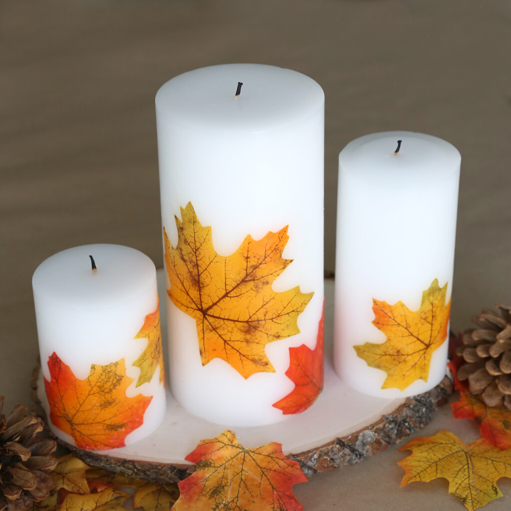 White pillar candles decorated with fall leaves
