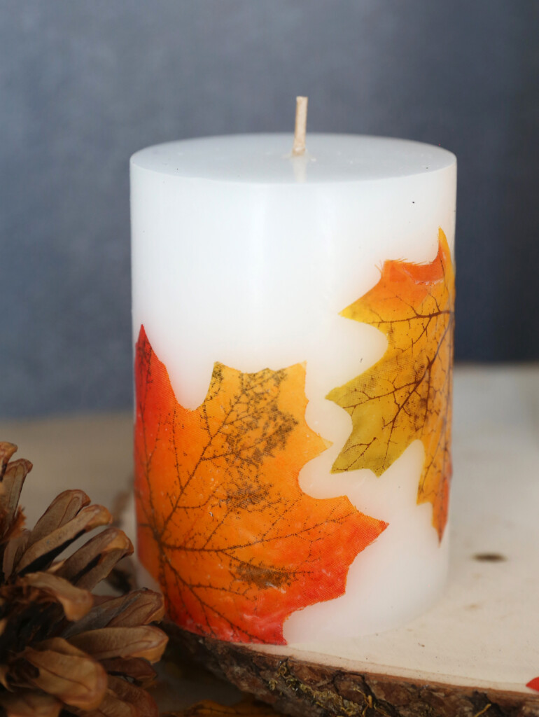 White pillar candle decorated with fall leaves