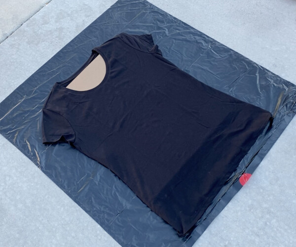 Black t-shirt with cardboard inside it on a black trash bag