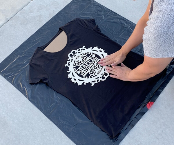 Hands sticking wood sign to t-shirt