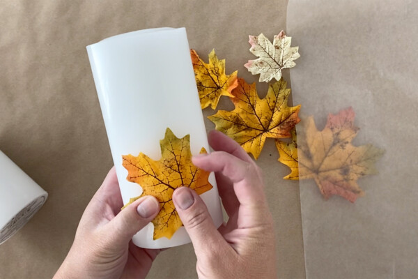 Hand placing faux leaf on a candle