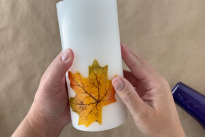 Hand rubbing excess wax off leaf on candle