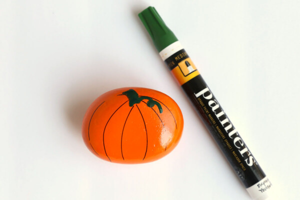 Rock painted orange with stem drawn and green paint pen