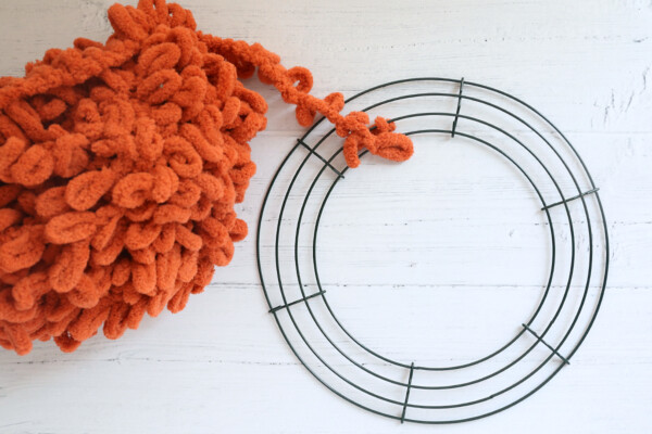 Orange loop yarn tied to circular wreath form