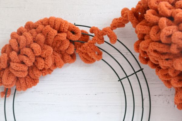 Orange loop yarn wrapped around wreath form