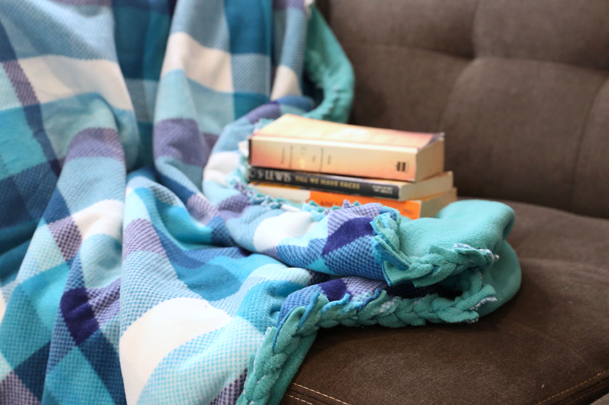 No sew fleece blanket with a braided edge on a couch with books