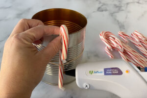 Hot gluing a candy cane to the can
