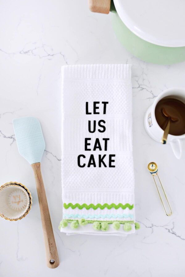 Decorated tea towel that says "let us eat cake".