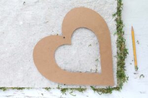 Tracing a wood heart on the back lining of a moss sheet.