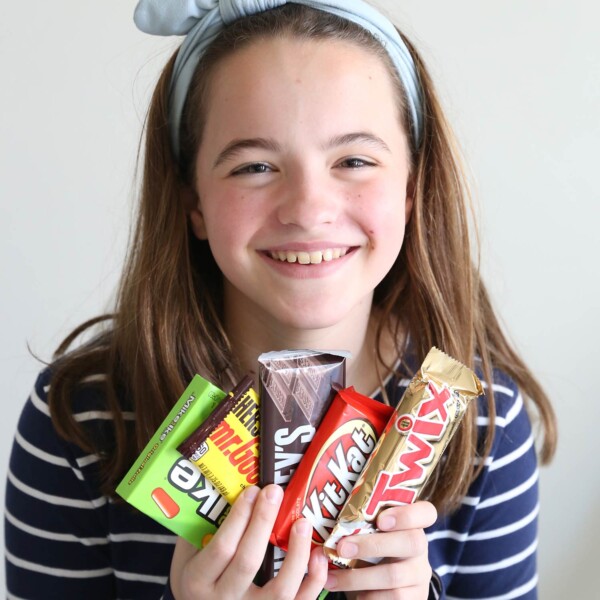 Girl smiling while holding candy bars.