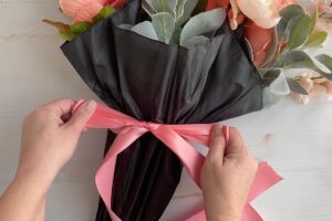 Hand tying a bow around the umbrella.