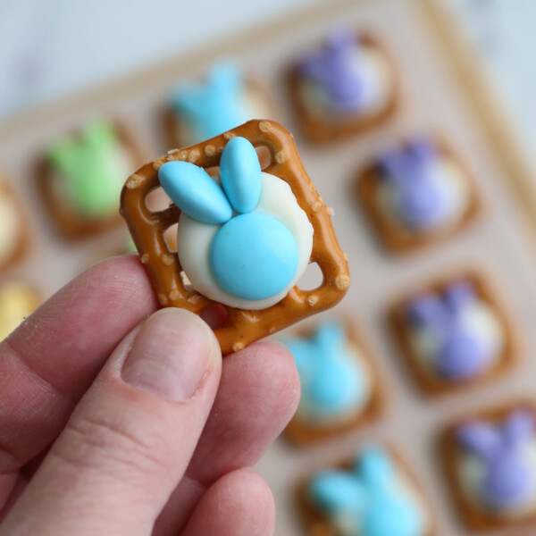 Hand holding a pretzel topped with M&Ms that look like a bunny head.