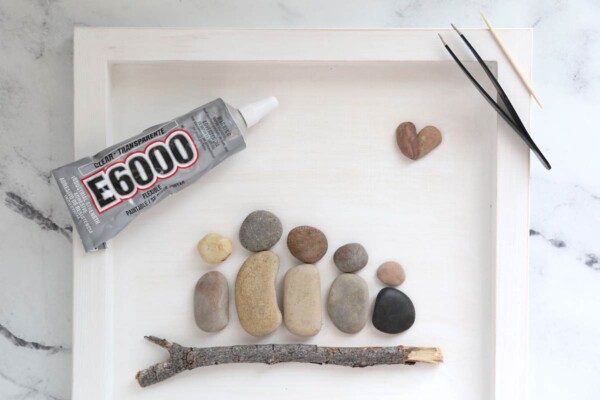 Pebbles arranged in family portrait with E6000 glue, tweezers, toothpick.