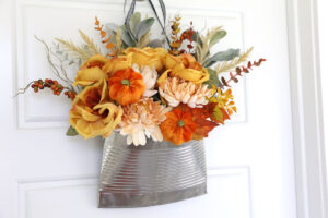 Door hanger made from a smashed metal can full or fall florals