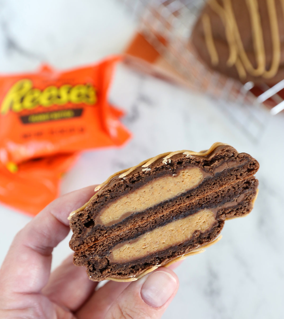 Hand holding peanut butter cup cookie cut in half