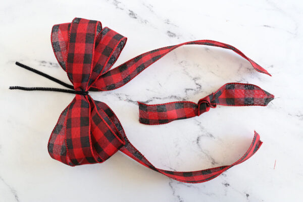 Three loops of ribbon fluffed; short piece of ribbon with knot in center.