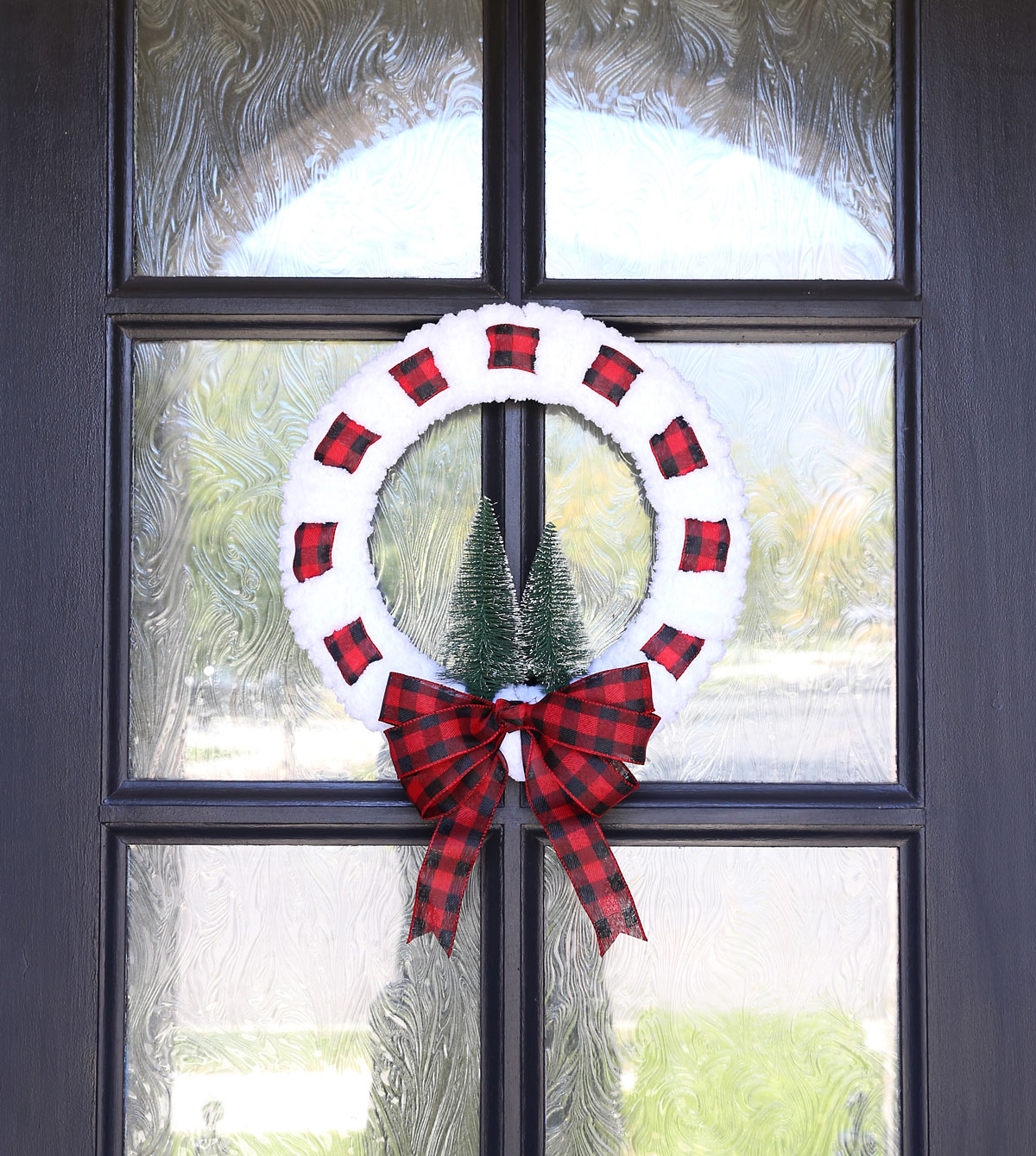 Yarn and ribbon wreath hanging on a door.