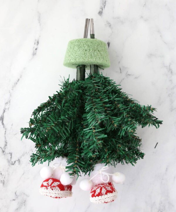 Two small artificial Christmas trees with posts going into the same foam round.