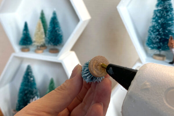 Putting hot glue on the bottom of a small tree.