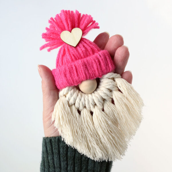 Hand holding a macrame gnome with a pink hat.