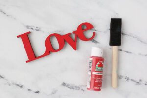 Wooden "love" cutout painted red, foam paintbrush and red paint