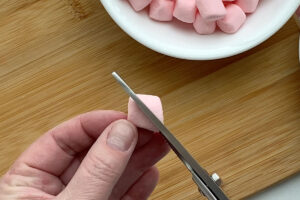 Cutting a mini marshmallow in half diagonally.