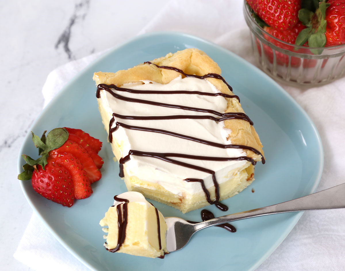 Slice of cream puff cake with one bite on a fork.