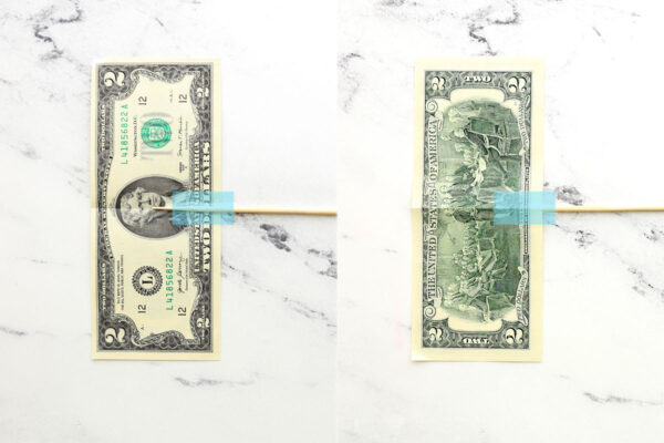 Dollar bill with skewer taped to it.