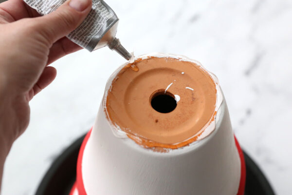 Applying glue to the bottom edge of a flower pot.