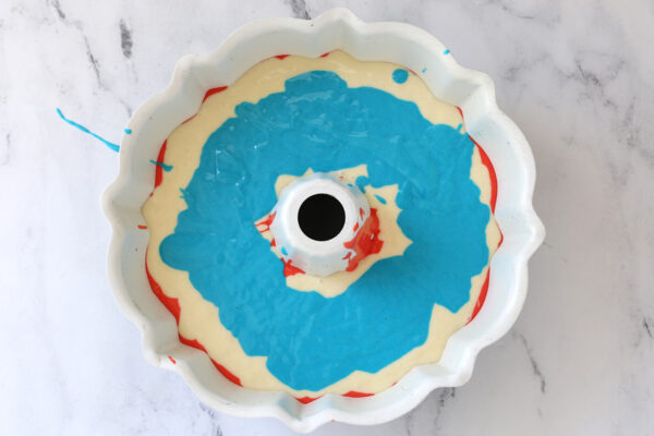 Red, white, and blue cake batter in a bundt cake pan.