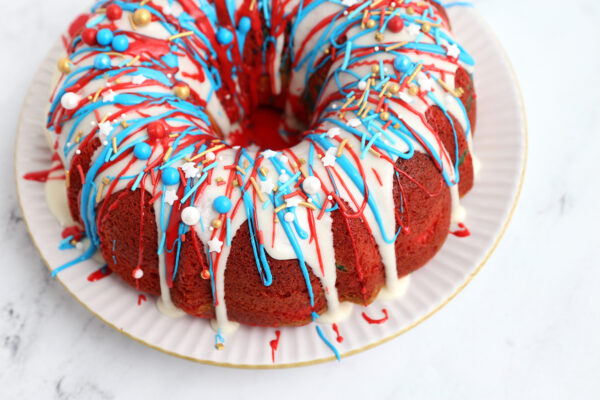 Cake decorated with white frosting, drizzled with red and blue frosting, sprinkles.