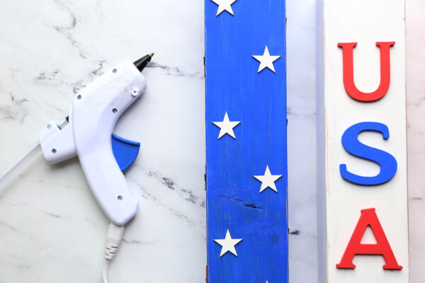Hot glue gun; stars glued onto blue wood piece, USA letters glued onto smallest piece.