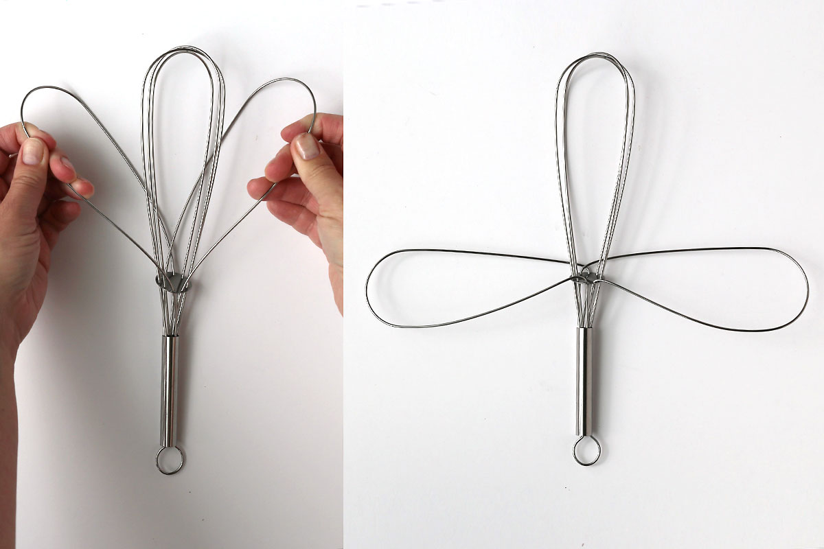 Pulling the top two loops out to the sides to create wings.