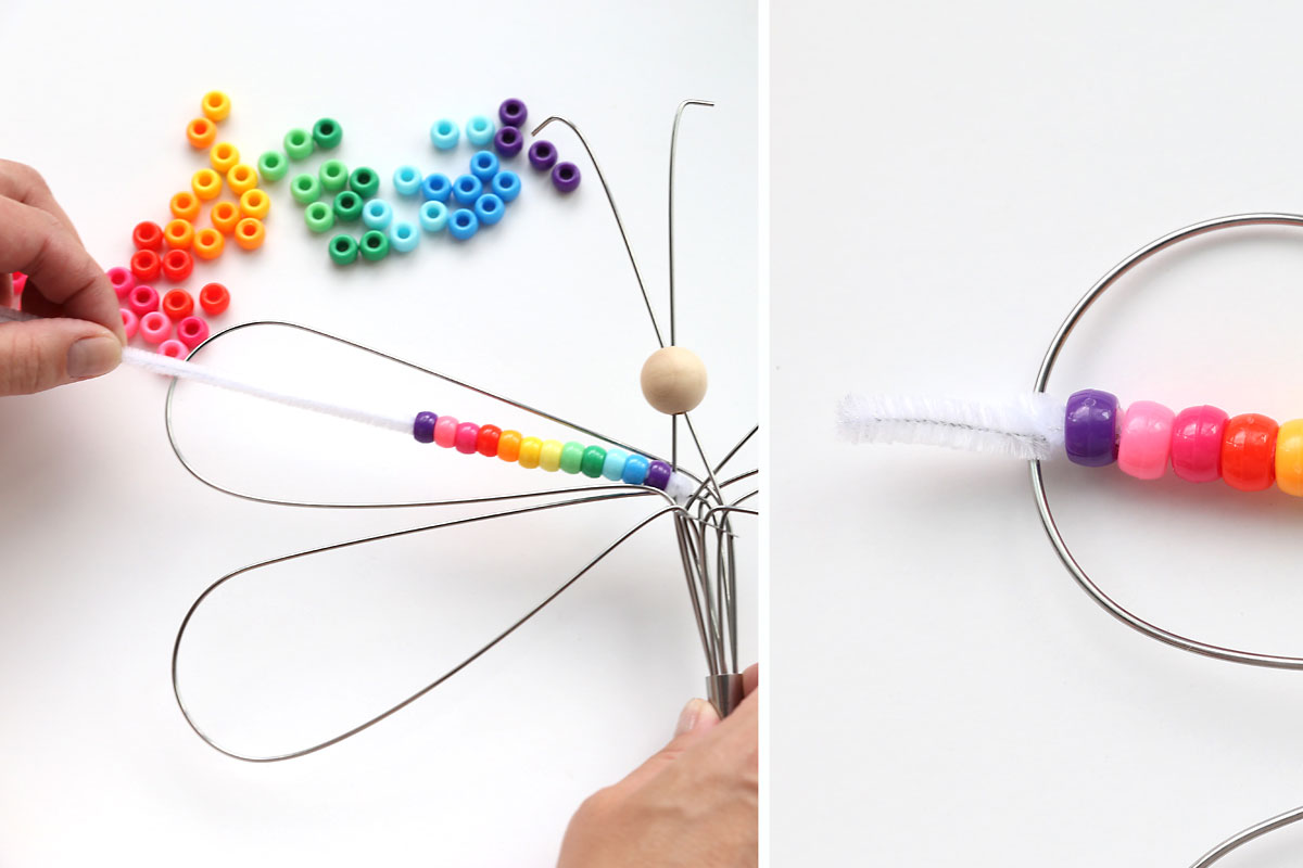 Stringing colorful beads onto the pipe cleaner, then securing it to the outside of a wing.