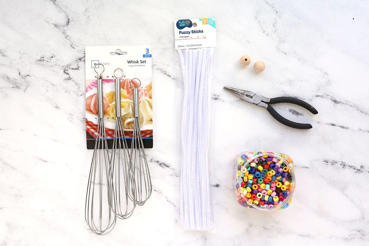 Metal whisks, white pipe cleaners, wood beads, pliers, colorful beads.