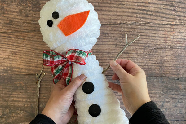 Buttons glued on body; pushing sticks into side of body for arms.