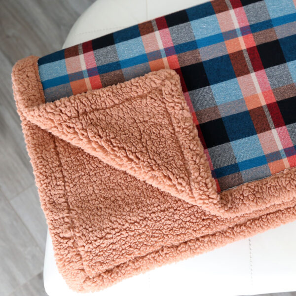Flannel blanket with corner turned up to show sherpa lining.