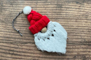 Hot glue white pom pom on top of hat.