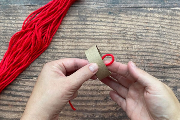 Placing fold of yarn inside toilet paper tube.