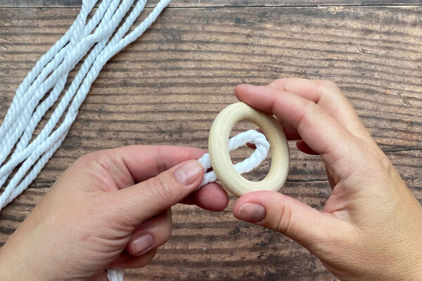 Loop of macrame cord placed through wooden ring.