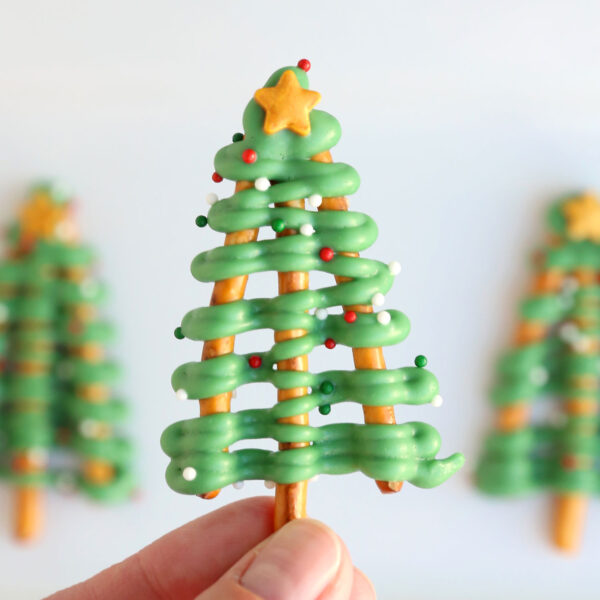 Hand holding a pretzel Christmas tree treat.