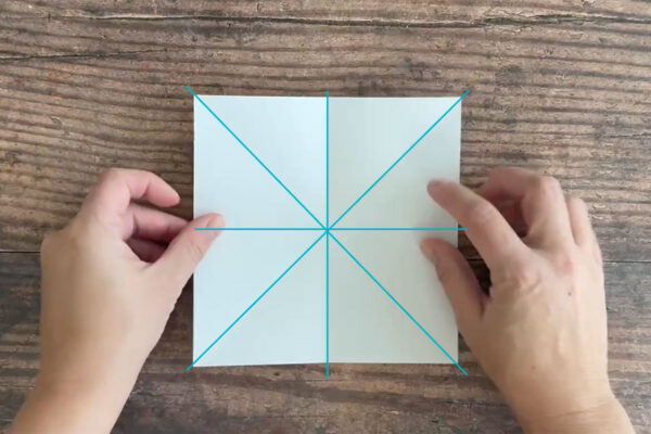 Square of paper with vertical, horizontal, and diagonal folds.
