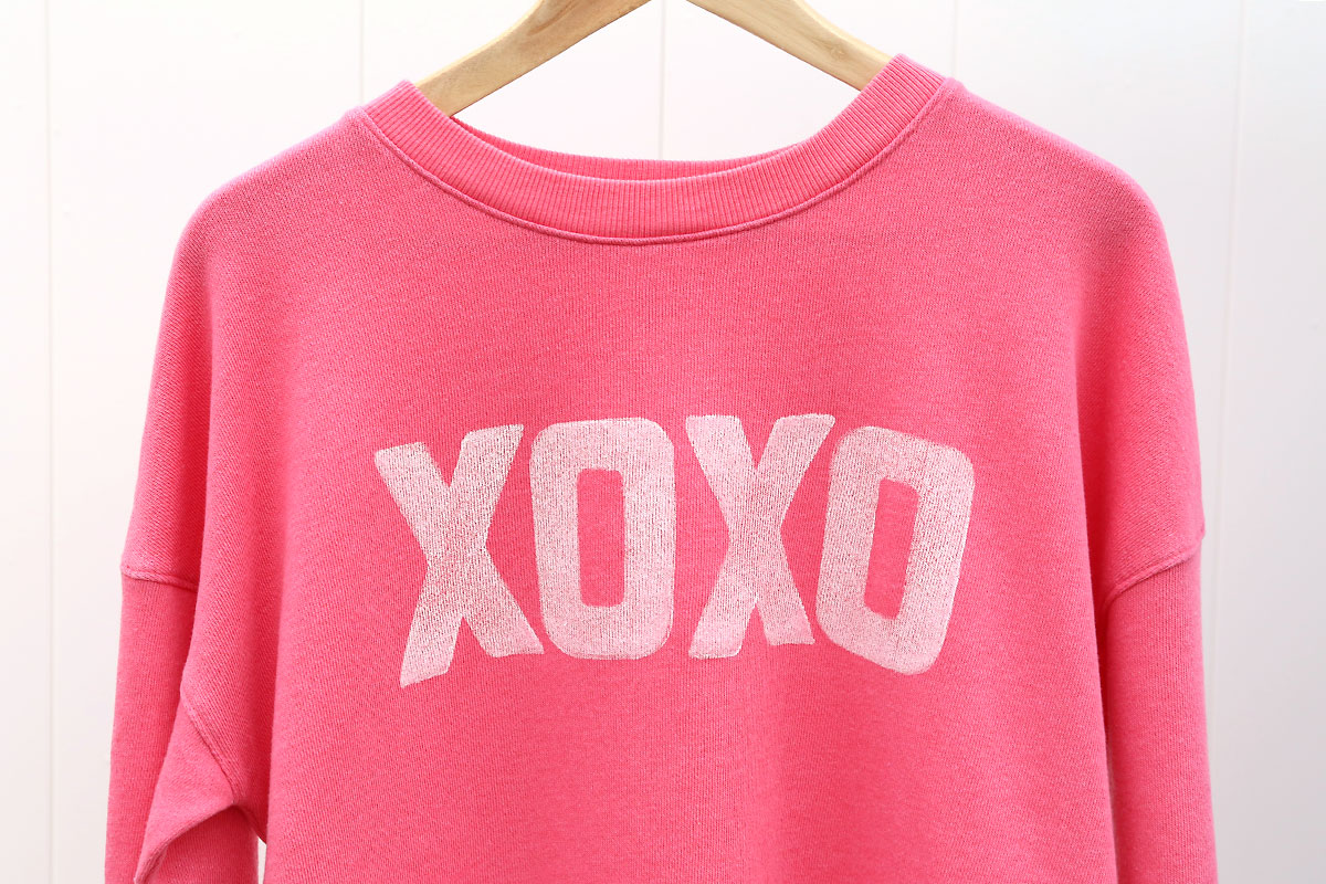 Pink sweatshirt with XOXO stamped on the front.