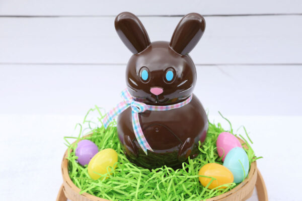 Faux chocolate bunny in a basket with Easter grass and eggs.