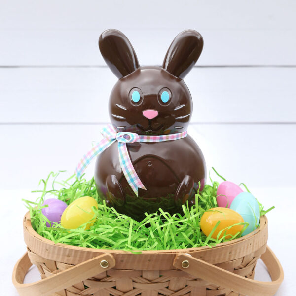 Faux chocolate bunny in a basket with Easter grass and eggs.